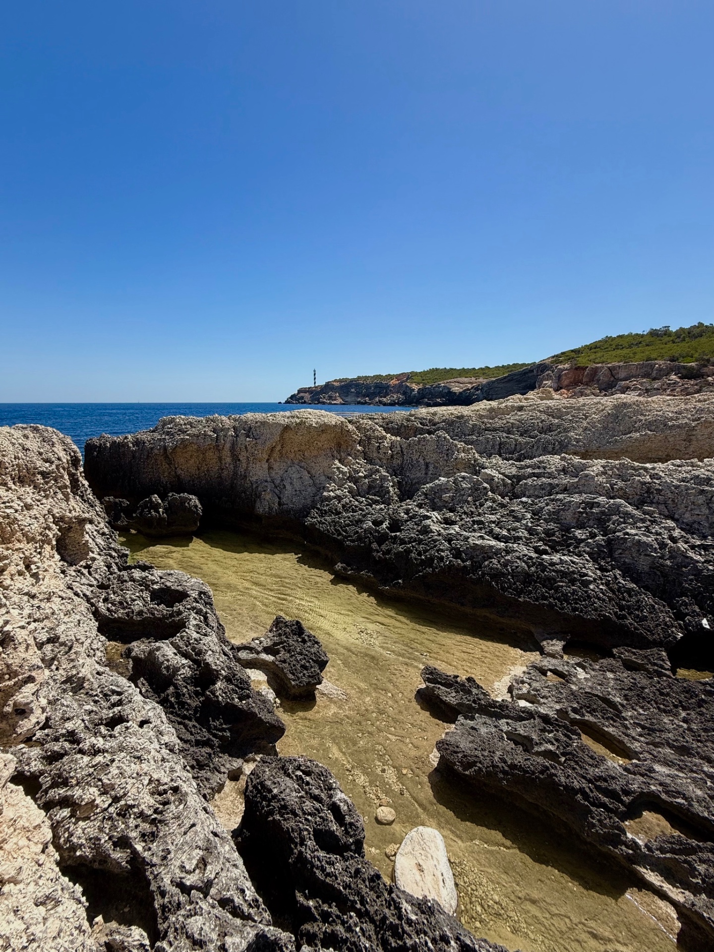 Tower of Light, natural rock pool with lighthouse in the distance