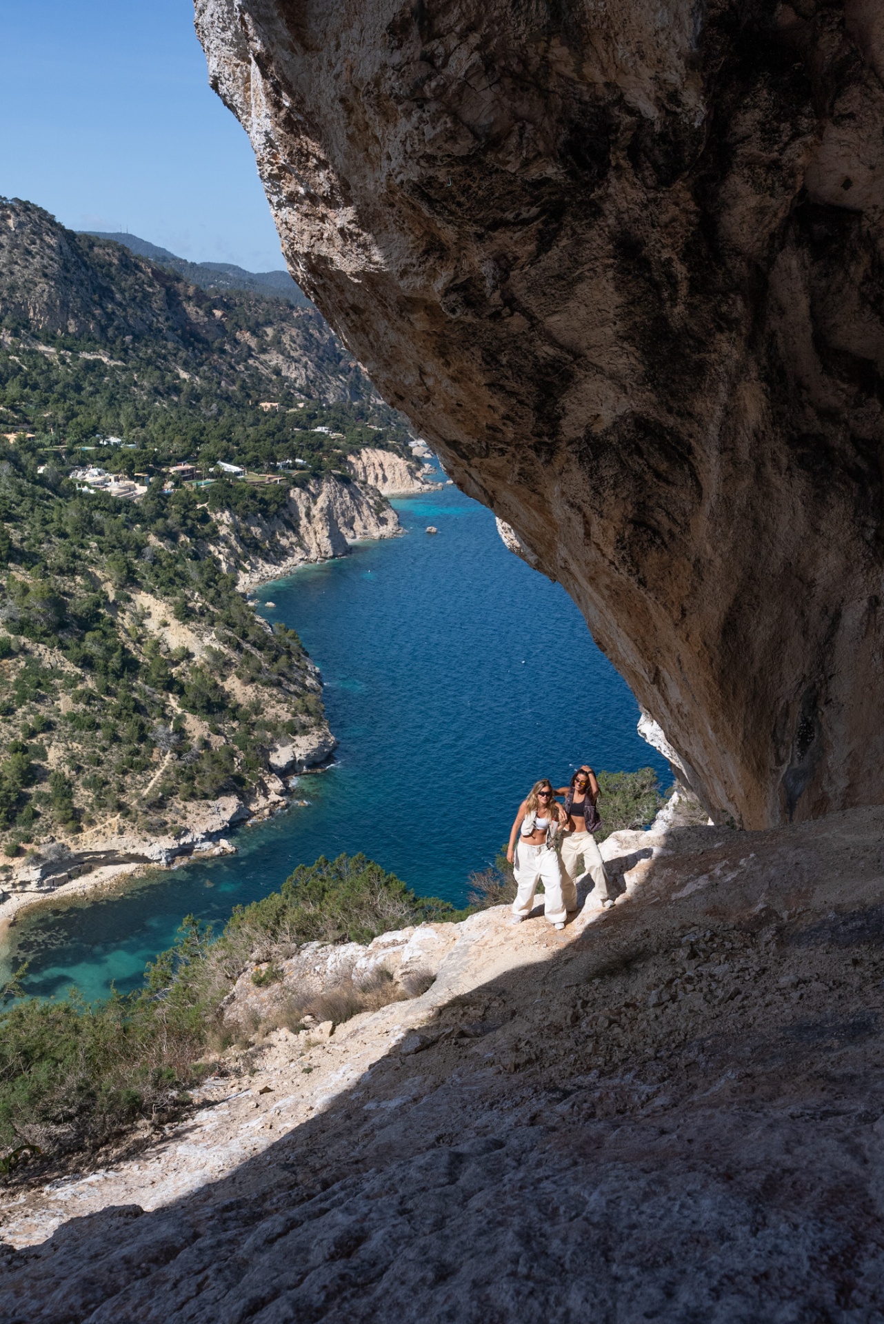 Queen of Hikes, two hikers on a cliff ledge beneath a dramatic arch