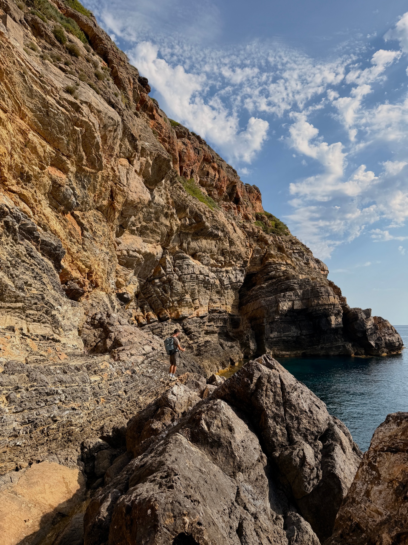 Hiker on the layered rock coastal traverse