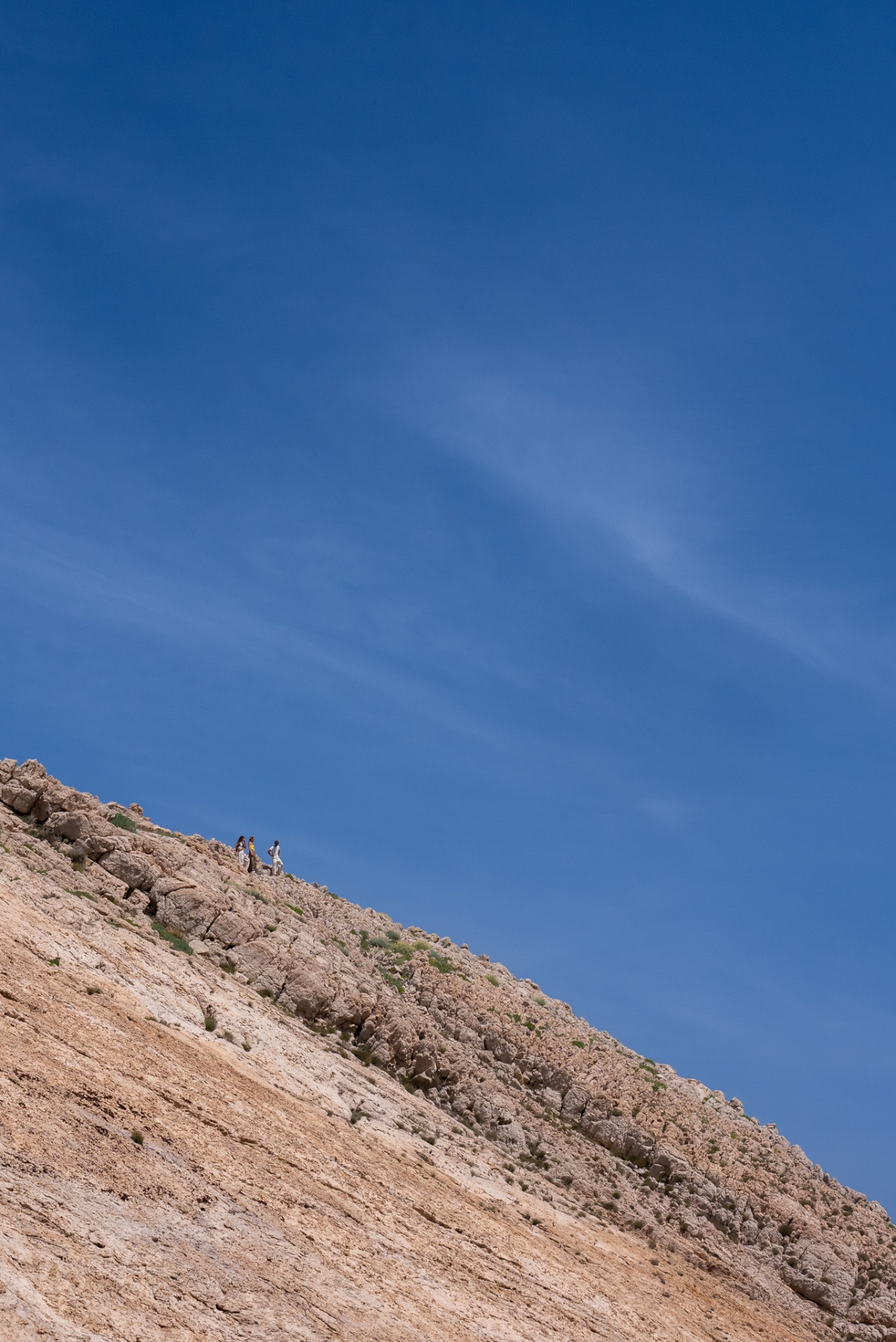 Laguna Love, tiny hikers crossing the pale rocky ridge under open sky